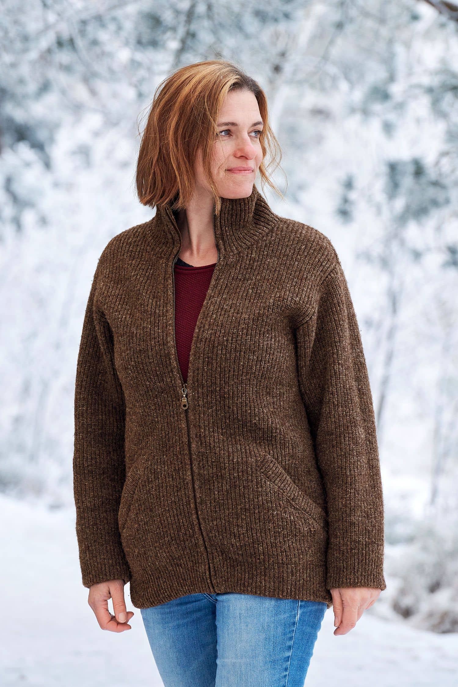 Frau in Schneelandschaft trägt eine braune Finkhof Jacke aus bio Wolle (kbT) und ein rotes Shirt