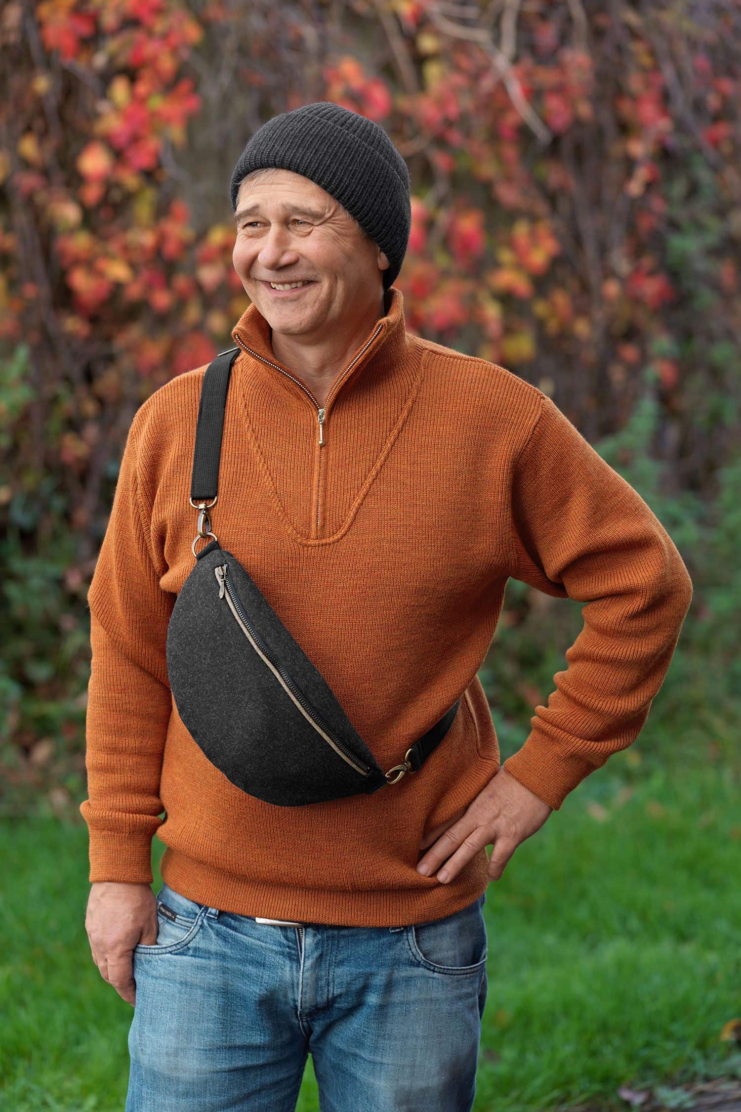 Mann mit orangem Pulli trägt anthrazitfarbene Bauchtasche aus Loden (Webstoff aus Schurwolle) vom Finkhof