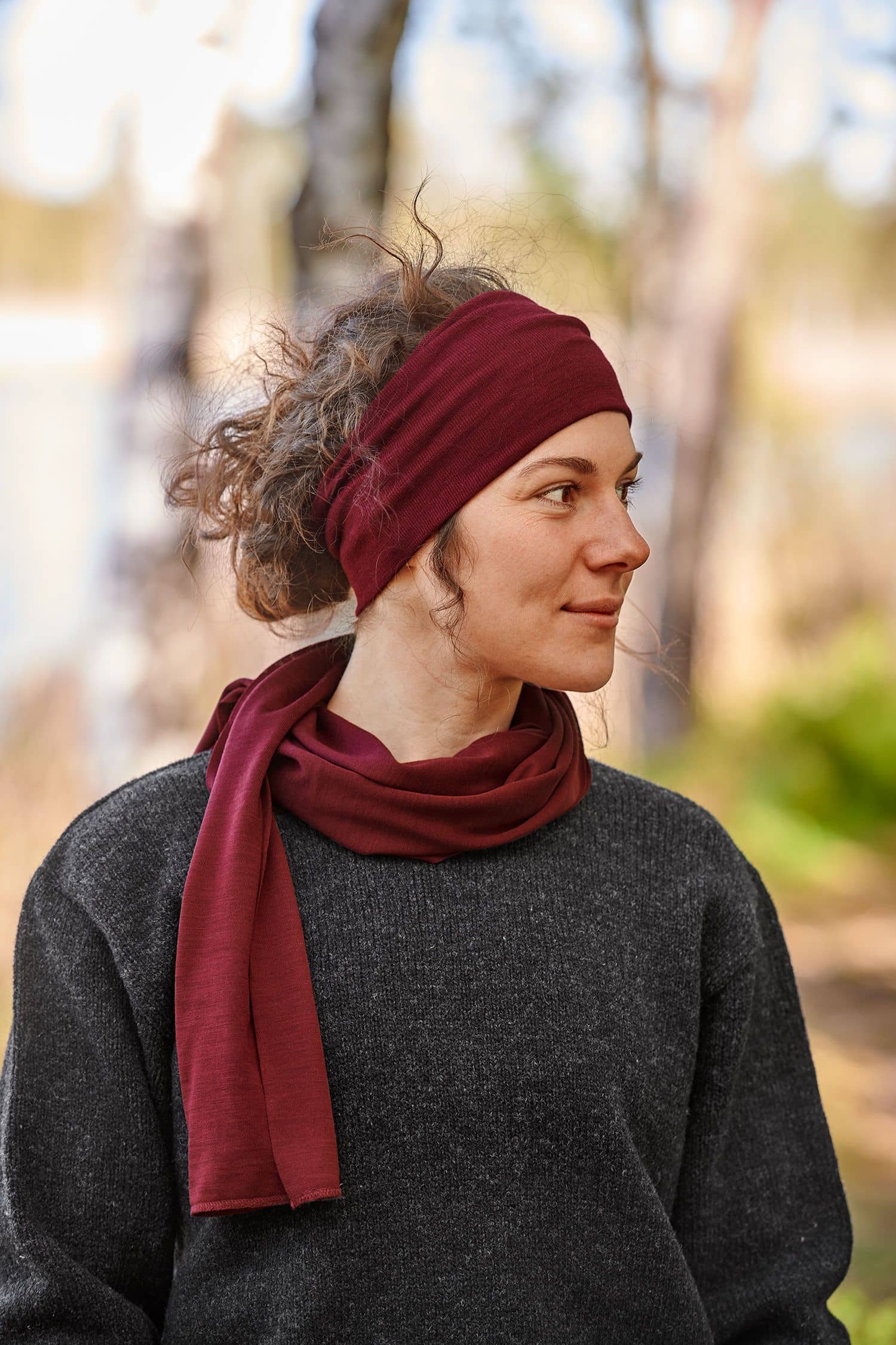Frau mit grauem Pulli trägt ein bordeauxrotes Stirnband aus bio Wolle (kbT) und Seide mit passendem Schal