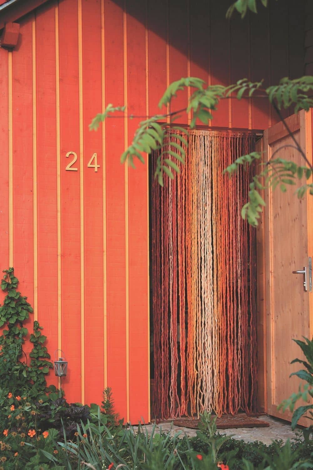 rotes Haus mit offener Tür in der ein Türvorhäng in rot, orange und gelb vom Finkhof hängt