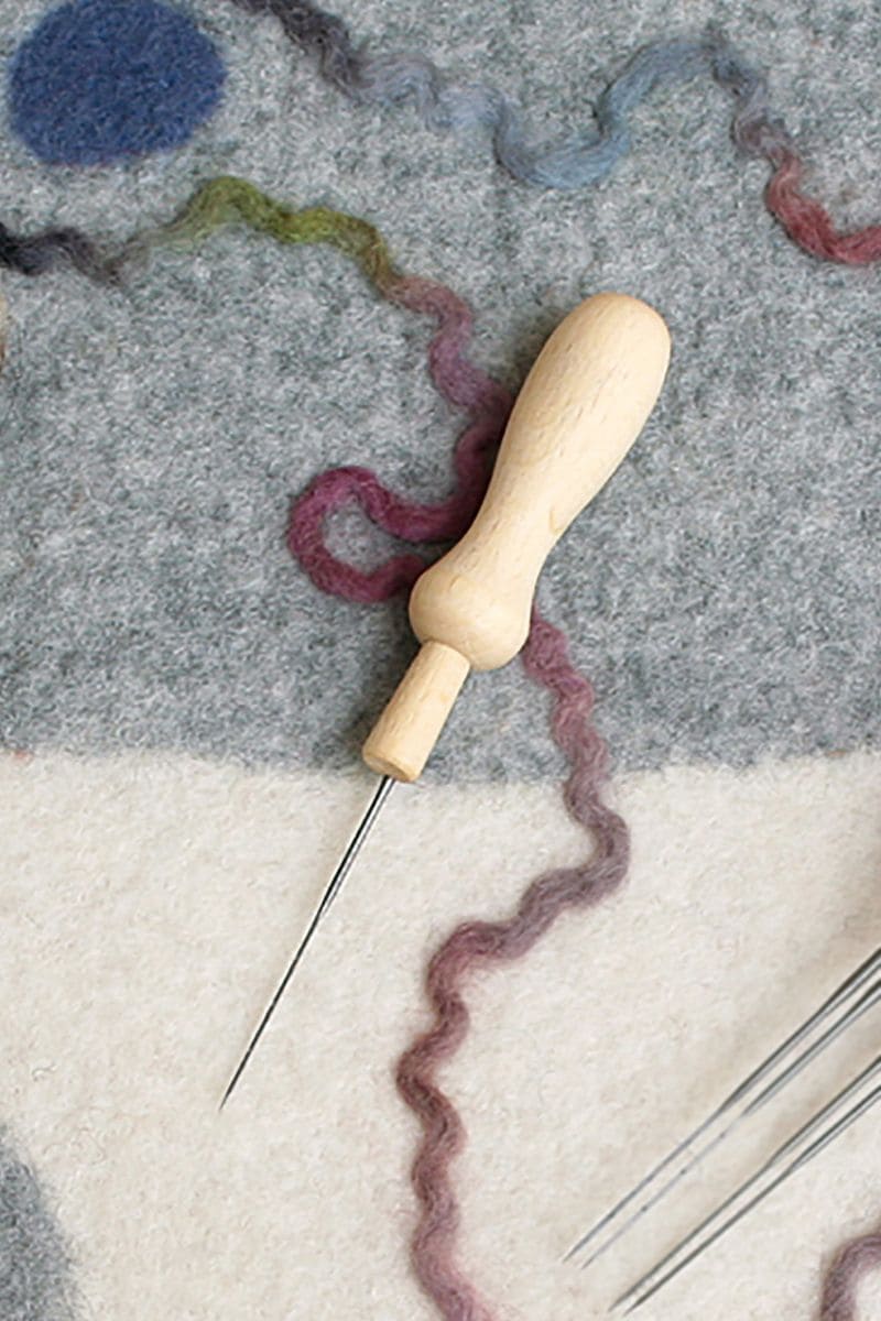 Filznadelhalter für 1 Nadel Filznadelhalter für eine Nadel mit Holzgriff auf grau gemustertem Untergrund