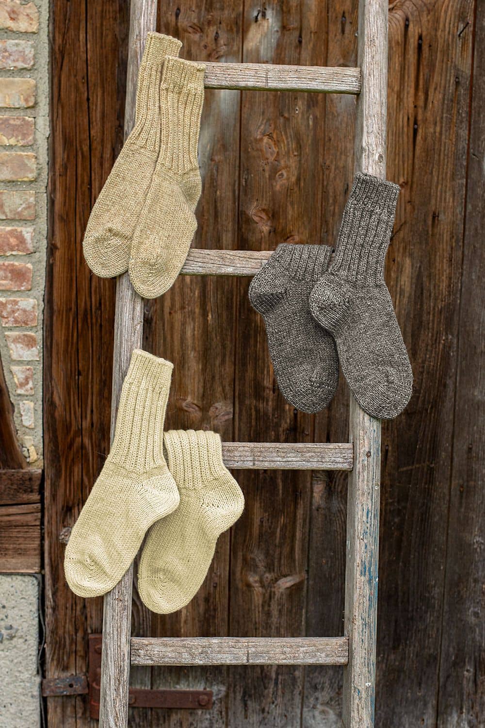 Dicke Finkhof-Socken dicke Finkhof Socken aus bio Wolle (kbT) in allen drei Farben als Paare über Holzleiter gehängt vor brauner Holzwand