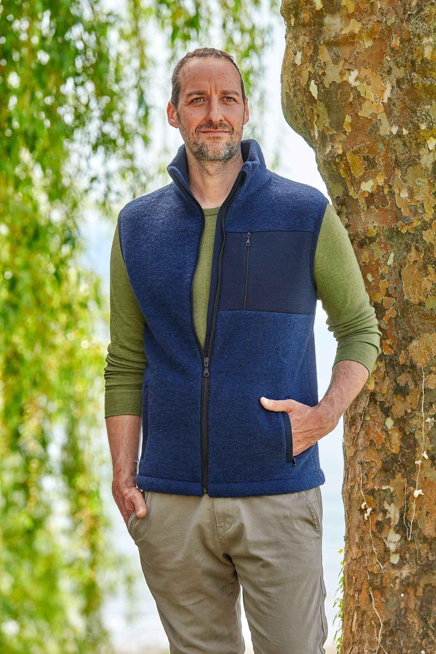 Mann trägt ein grünes Langarmshirt und eine marineblaue Wollfleece Weste aus bio Merinowolle (kbT) vom Finkhof
