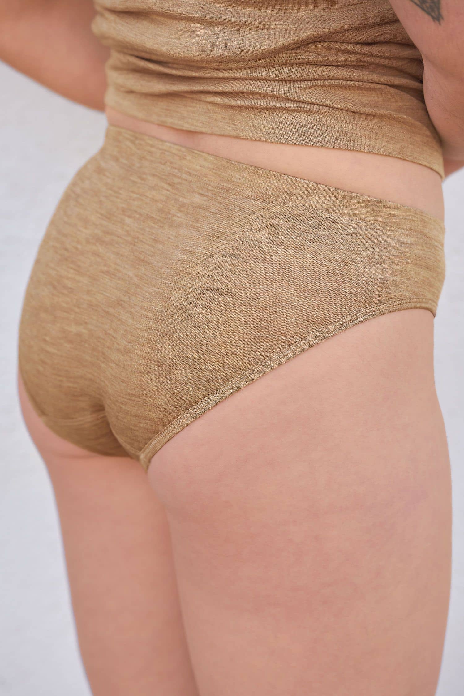 Rückansicht von Frau mit walnussbraunem Slip aus bio Wolle (kbT) und Seide