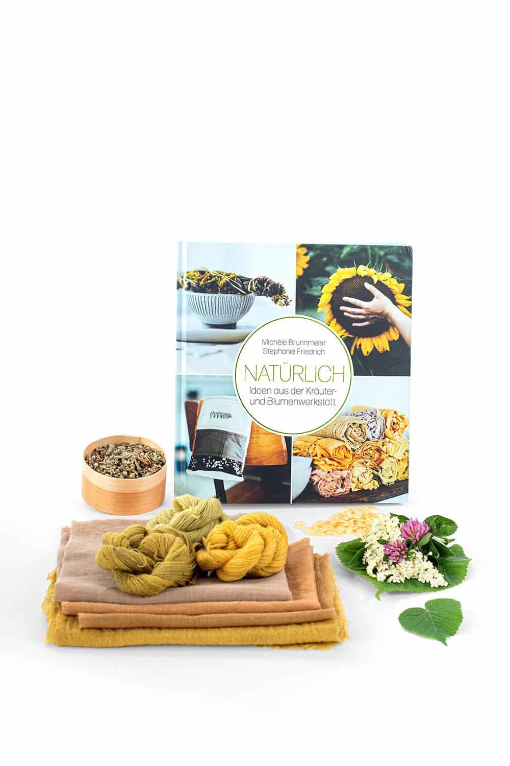 Natürlich: Ideen aus der Kräuter- und Blumenwerkstatt in der Mitte ist Buch ,,Natürlich: Ideen aus der Kräuter- und Blumenwerkstatt", davor liegen Stoffe und Pflanzenblätter
