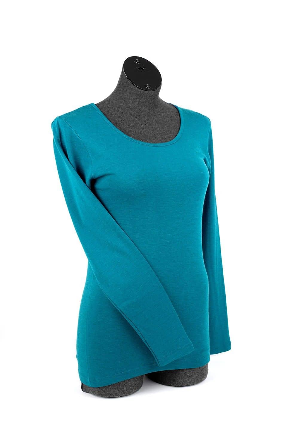 Frau mit Jeans und Gürtel trägt ein einfarbiges türkises Langarmshirt aus bio Wolle (kbT) und Seide