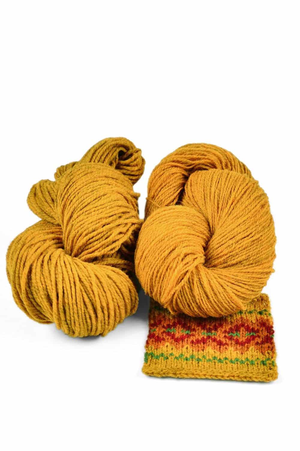 gelbmelierte dünne Finkhof Merinowolle aus bio Wolle (kbT) mit Strickstück davor, weißer Untergrund