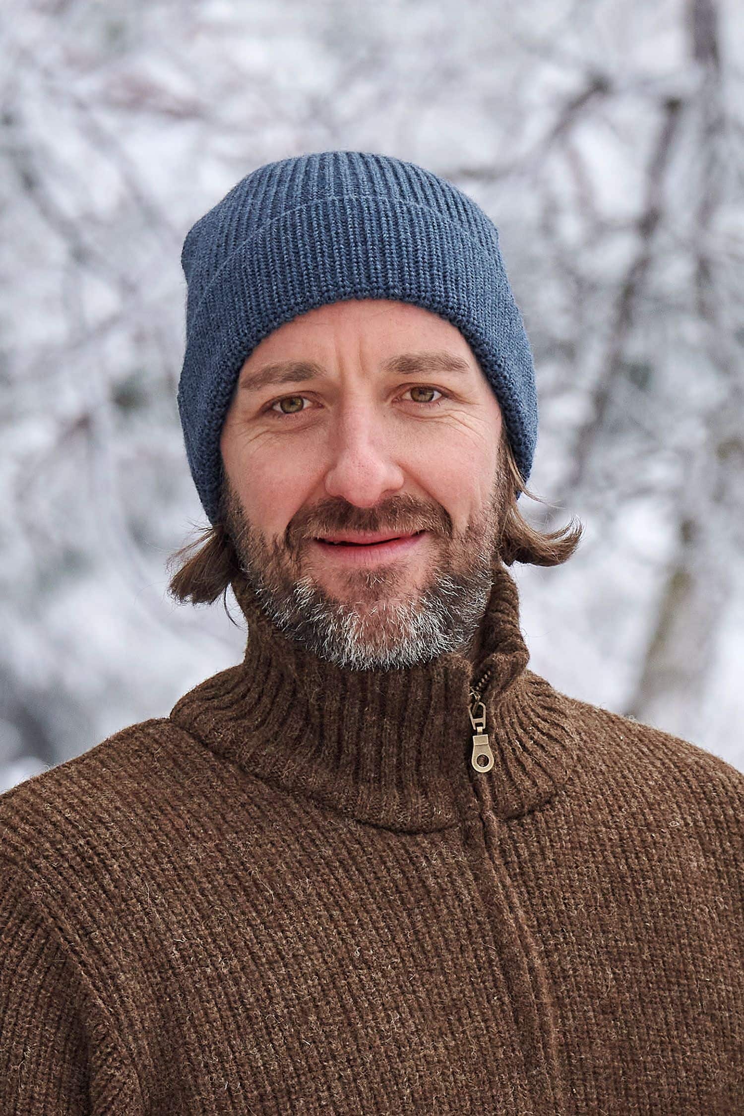 Mann mit brauner Weste trägt eine jeansblaue Wollmütze aus bio Wolle (kbT) vom Finkhof