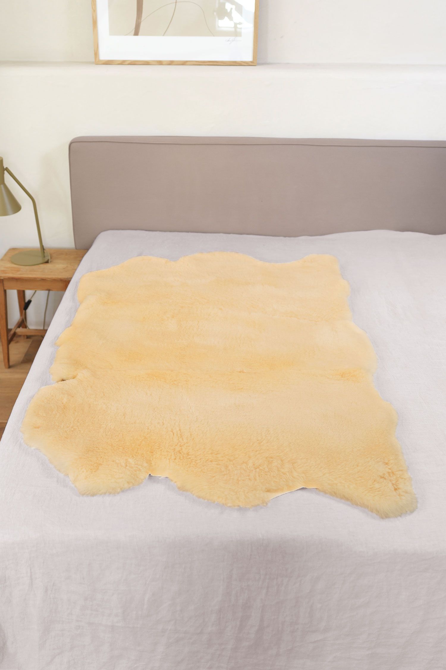 relugan gegerbte Felldecke in natürlicher Form aus Schaffell vom Finkhof auf grauem Bett