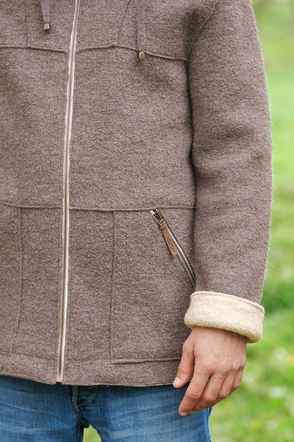 Bildausschnitt vom Ärmel der braunen Jacke mit beiger Innenseite und Reißverschluss aus bio Wolle (kbT) vom Finkhof