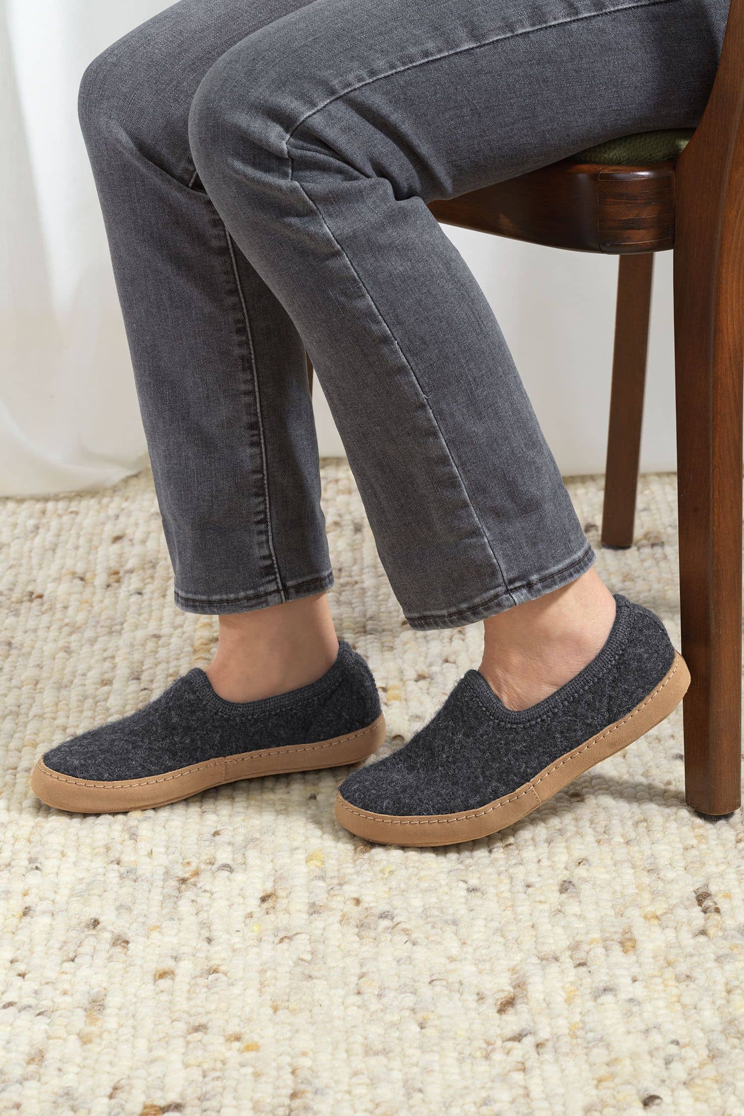 Person trägt graue Finkhof Hausschuhe aus bio Wolle (kbT), Sohle aus pflanzlich gegerbtem Rindsleder, seitlich zu sehen