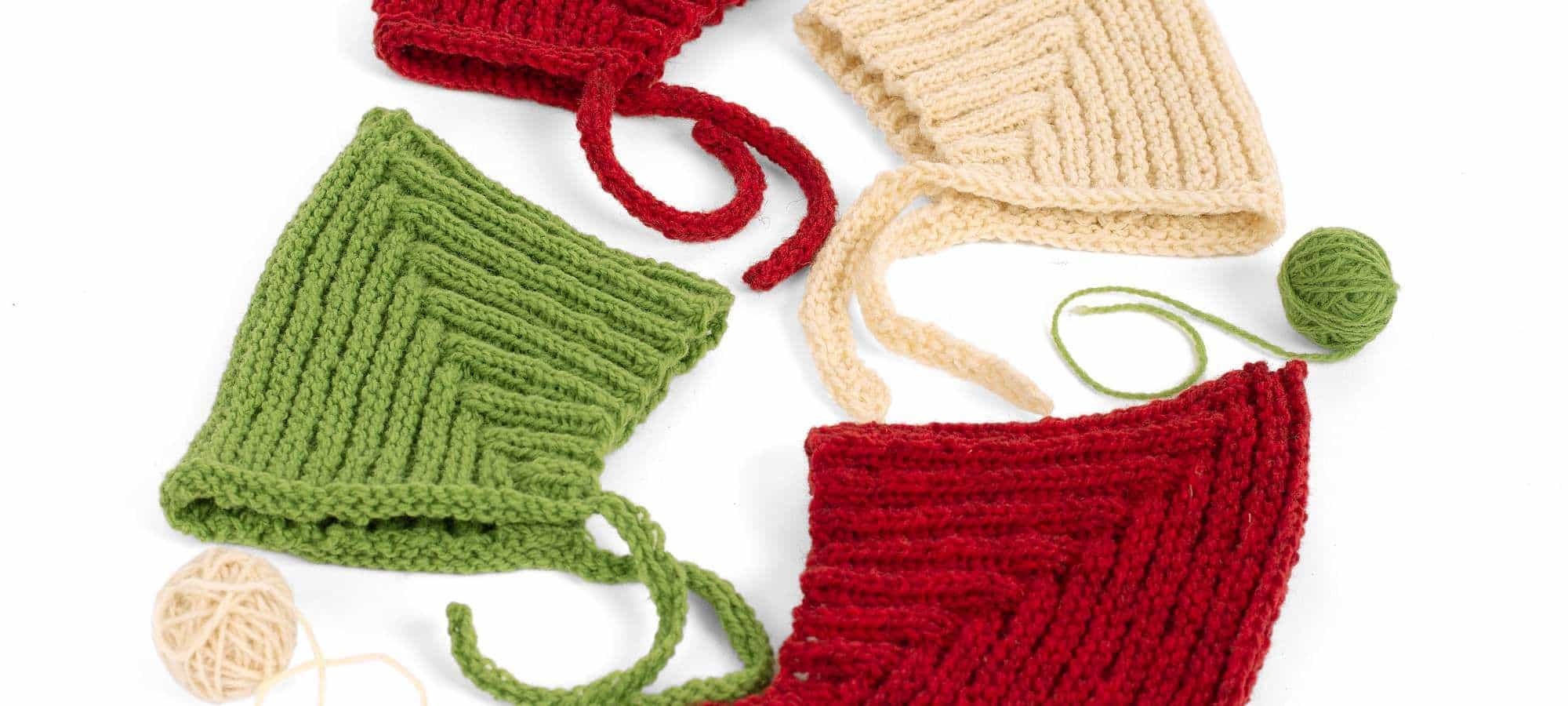Strickanleitung Zwergenmütze weiße, rote und grüne Zwergenmützen auf weißem Untergrund für Strickanleitung