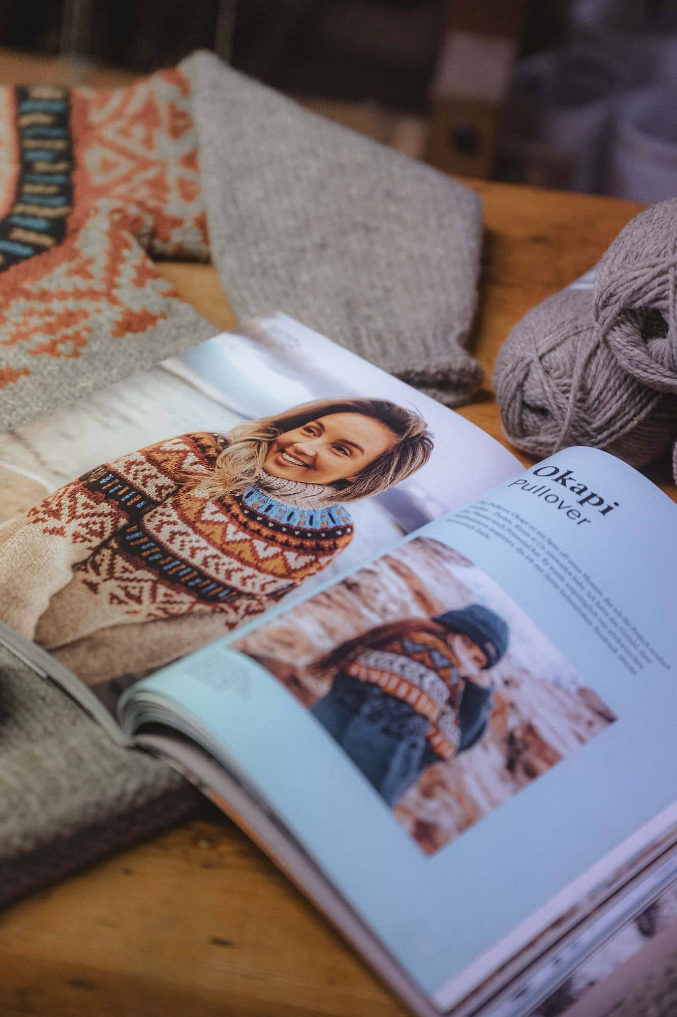 aufgeklapptes Exemplar, des Buchs ,,Einfach nordisch stricken - Farbenfroh2 mit Norwegerpulli im Hintergrund