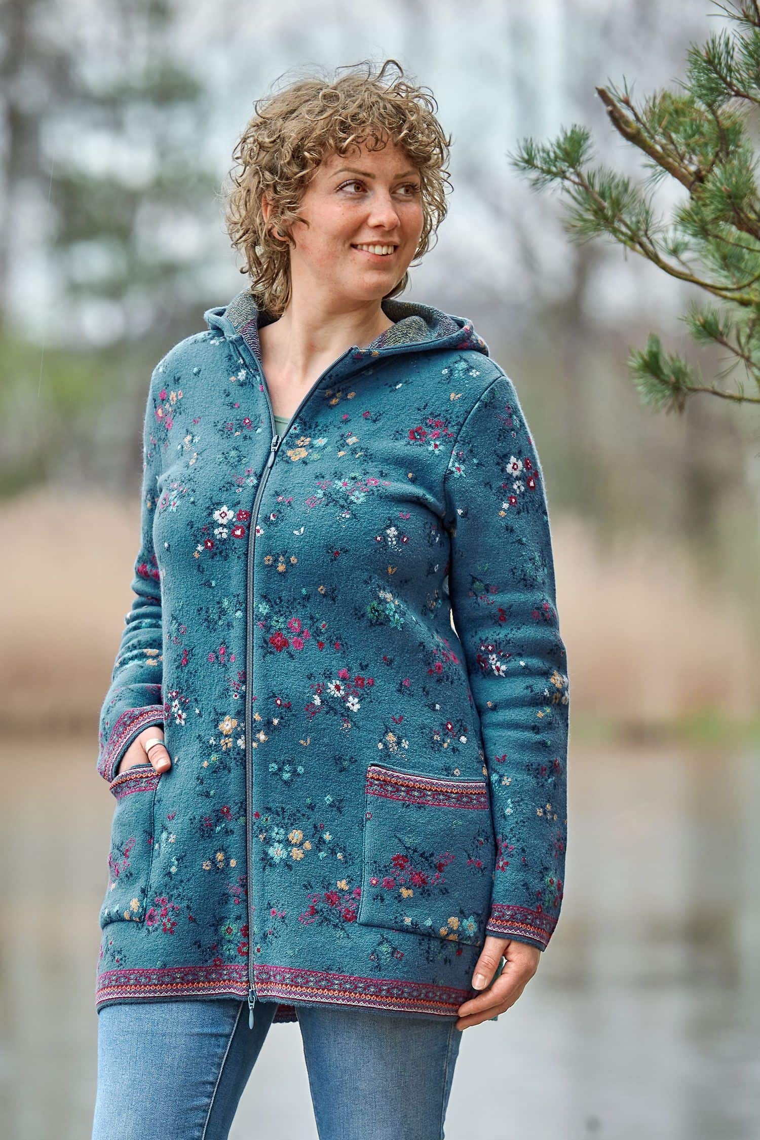 Frau von vorne mit langer blauer Kapuzenjacke aus Walkstoff mit bio Merinowolle (kbT) und Baumwolle (kbA) mit Blumenmuster