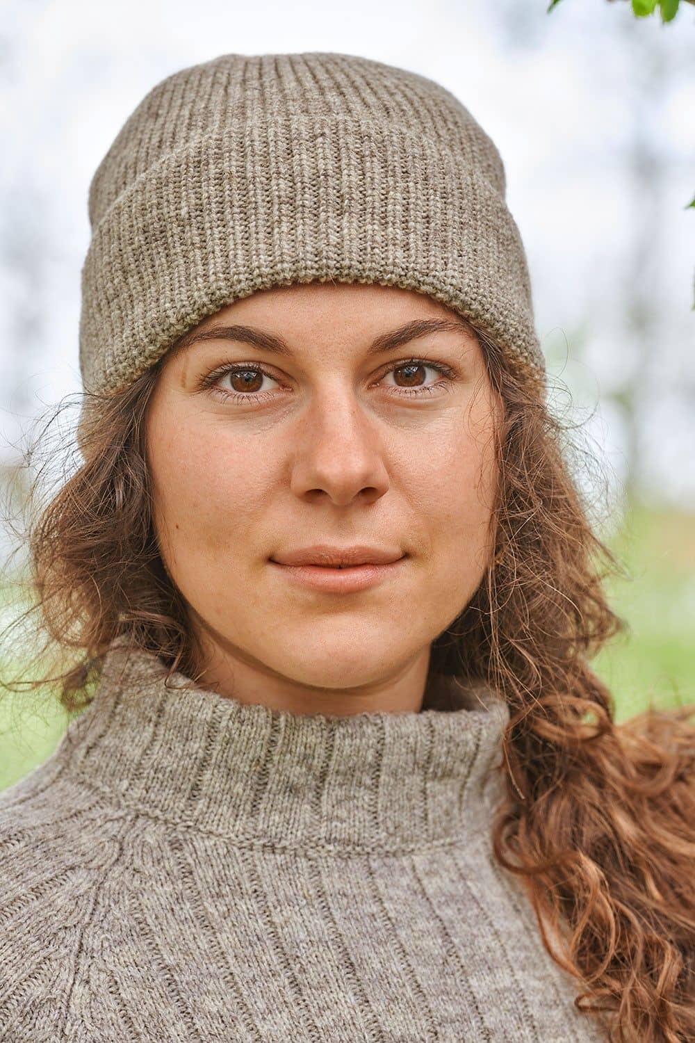 Portraitaufnahme von Frau mit grauem Strickpulli und grauer Finkhof Mütze aus bio Wolle (kbT)