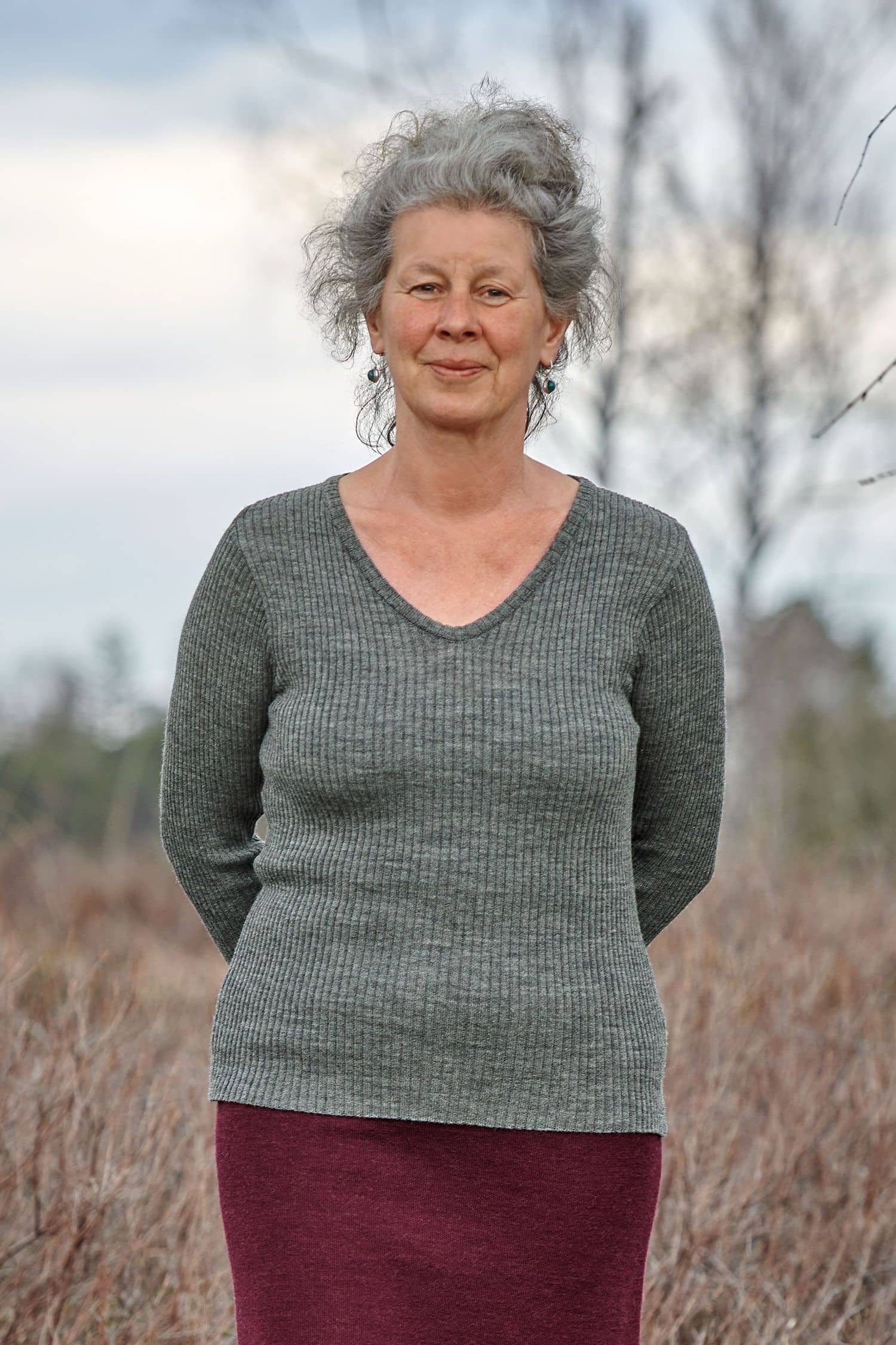 Frau trägt roten Rock und Pulli mit Rippstoff und V Ausschnitt aus bio Finkhof Wolle (kbT)