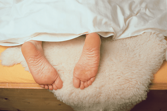 Einfach mal gepflegt abhängen – so einfach ist die Schaffellpflege weiße Felldecke auf einem gelben Lacken mit nackten Füßen