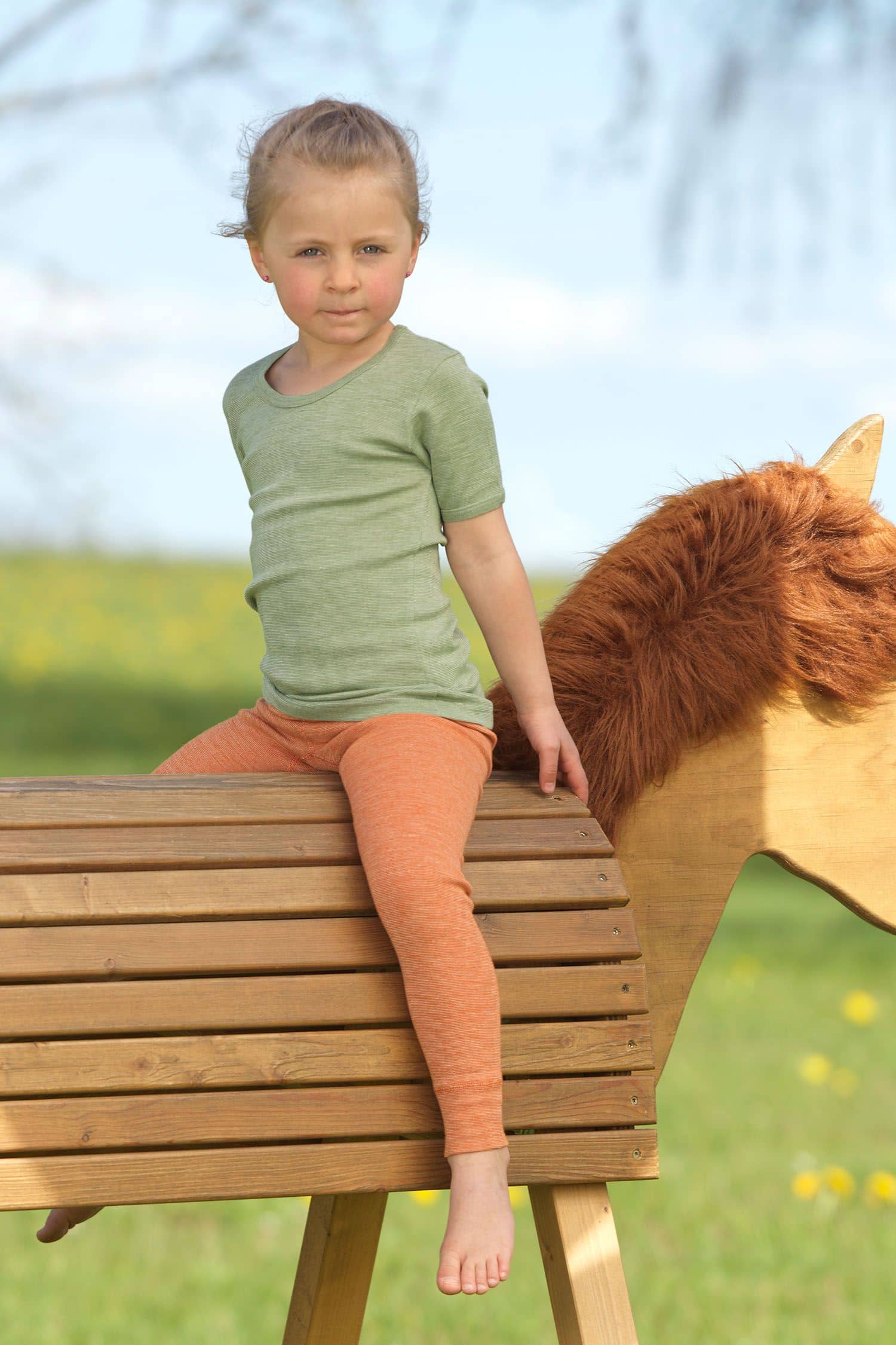 Mädchen sitzt auf Pferd und trägt Wollmix Unterwäsche aus bio Wolle (kbT), bio Baumwolle (kbA) und Seide