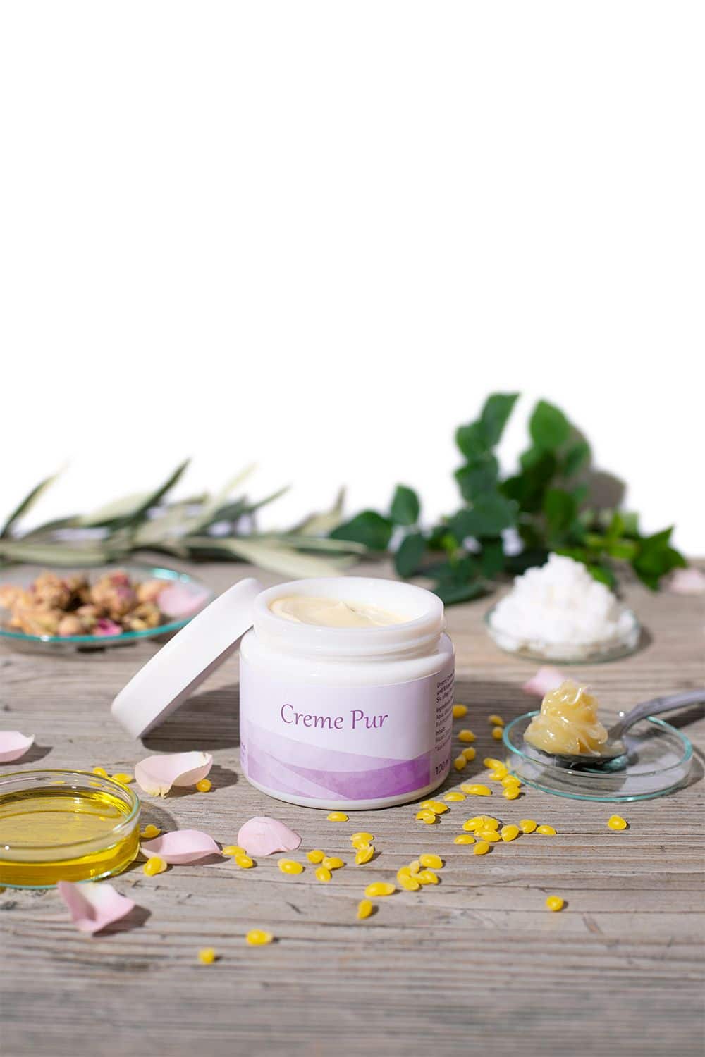 Finkhof Creme Pur in weißem Tiegel mit bio Produkten (kbA / kbT) auf Stimmungsbild mit Kräutern, Wachs und Ölen