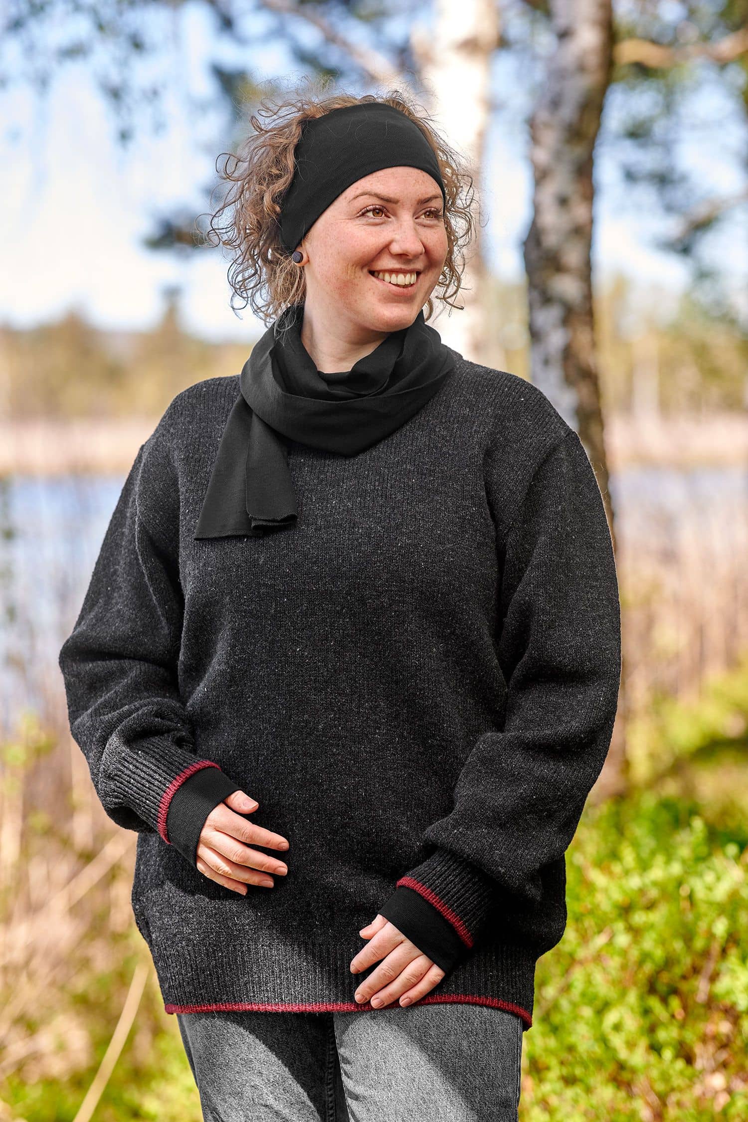 lachende Frau mit grauem Pulli trägt ein schwarzes Stirnband aus bio Wolle (kbT) und Seide mit passendem Schal