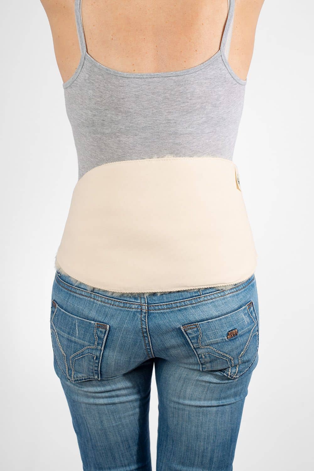 Model von hinten mit Top, Jeans und weißem relugan gegerbtem Finkhof Rückenwärmer aus Schaffell und kbA Baumwolle
