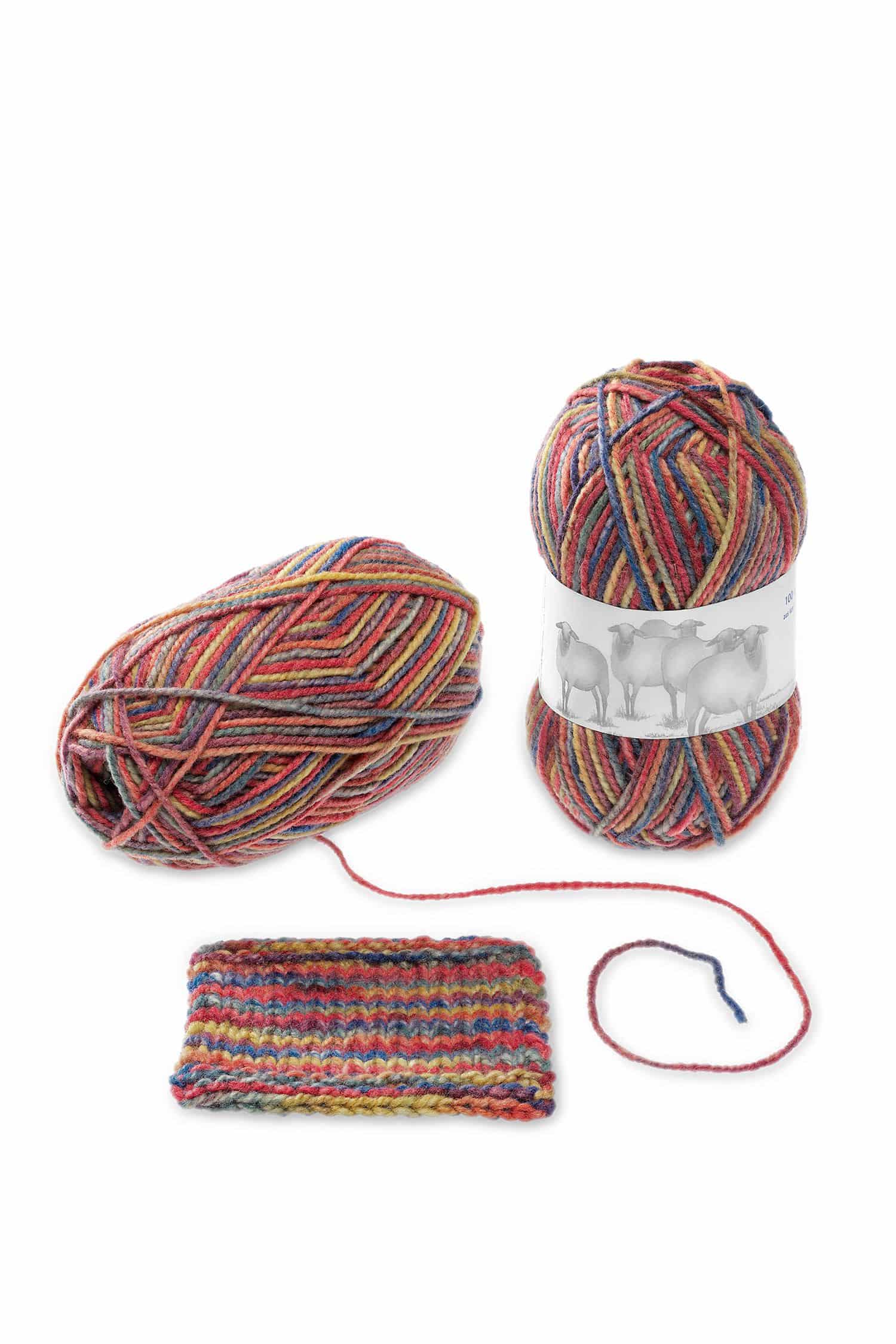 Wollknäule der Finkhof Merinowolle mit Farbverlauf Sommerbrise aus bio Wolle (kbT) mit Strickstück daneben, Freisteller