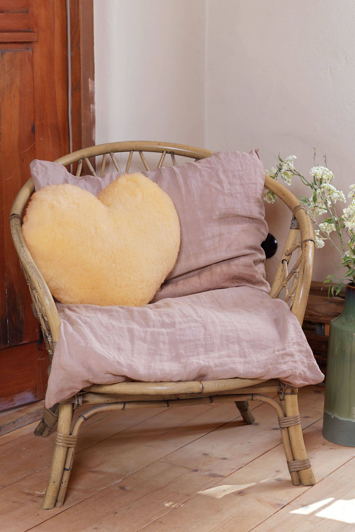 Kissen in Herzform aus relugan gegerbtem  Finkhof Schaffell liegt auf einem Korbstuhl