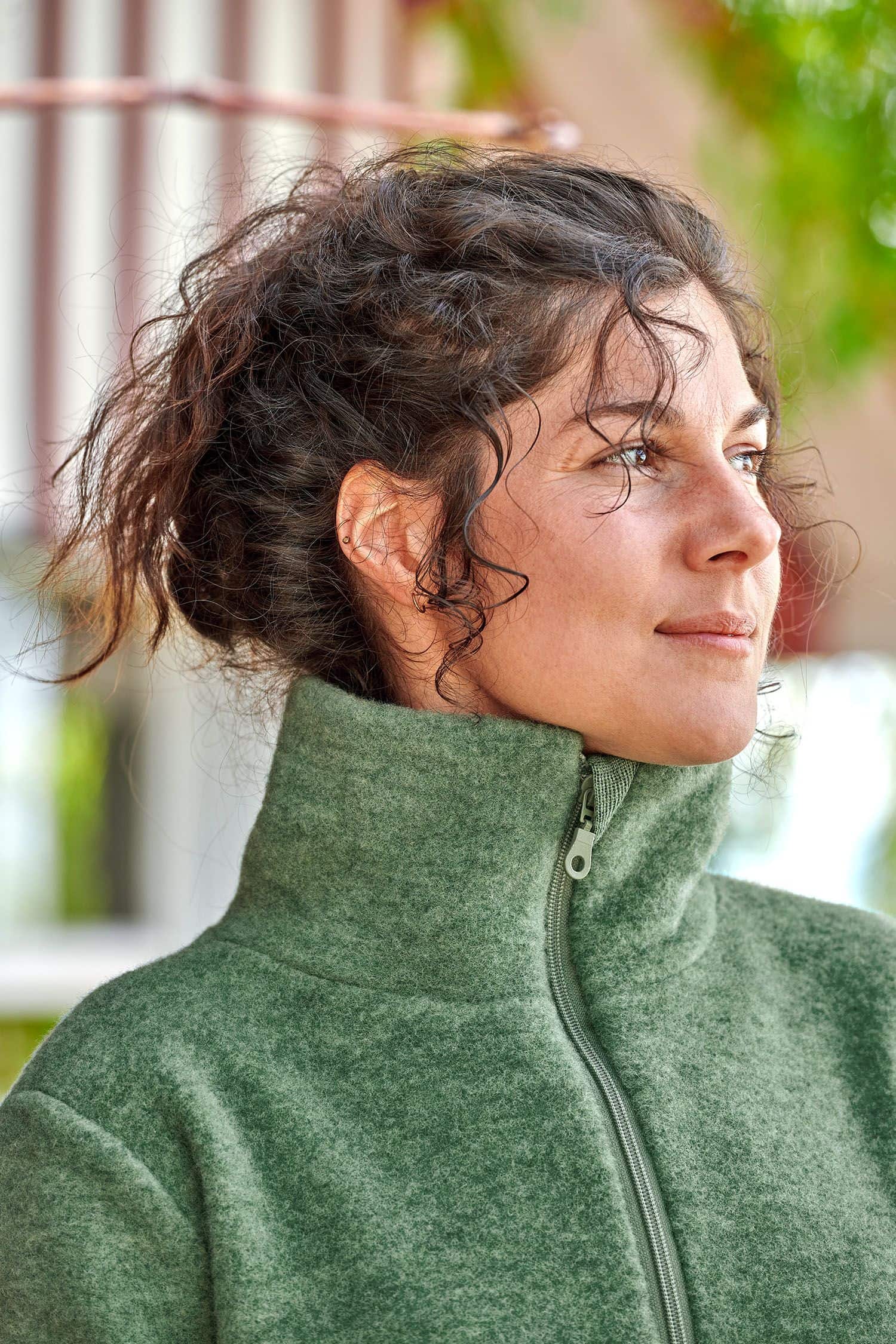 Portraitaufnahme von Frau mit grünem Pulli mit hohem Kragen und Reißverschluss aus bio Wolle (kbT) vom Finkhof