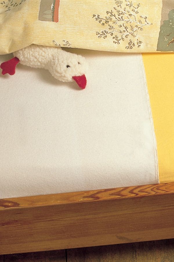 Bett mit gelbem Leintuch und weißer Moltonauflage mit 70x140cm aus bio Baumwolle (kbA) und Entenkuscheltier