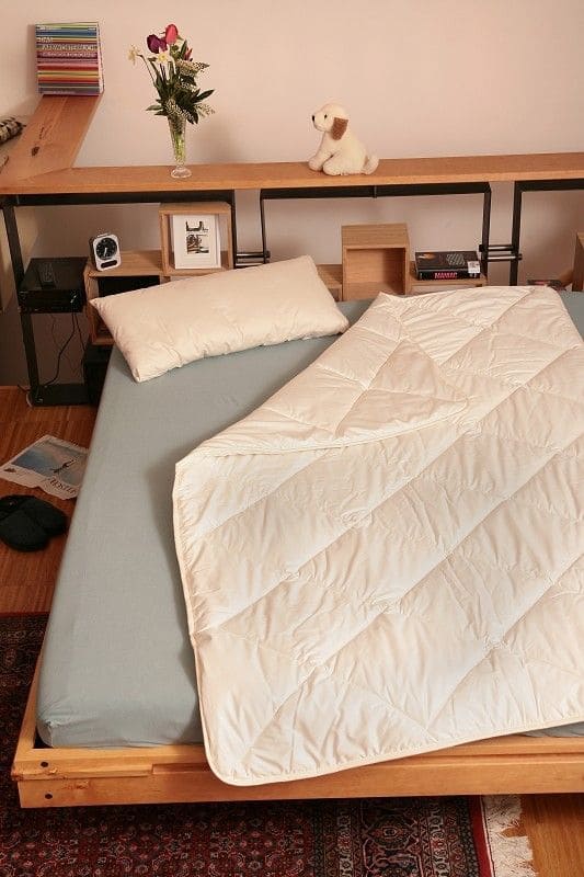 Bett mit Kissen und einer weißen Steppdecke aus bio Wolle (kbT) und bio Baumwolle (kbA) vom Finkhof