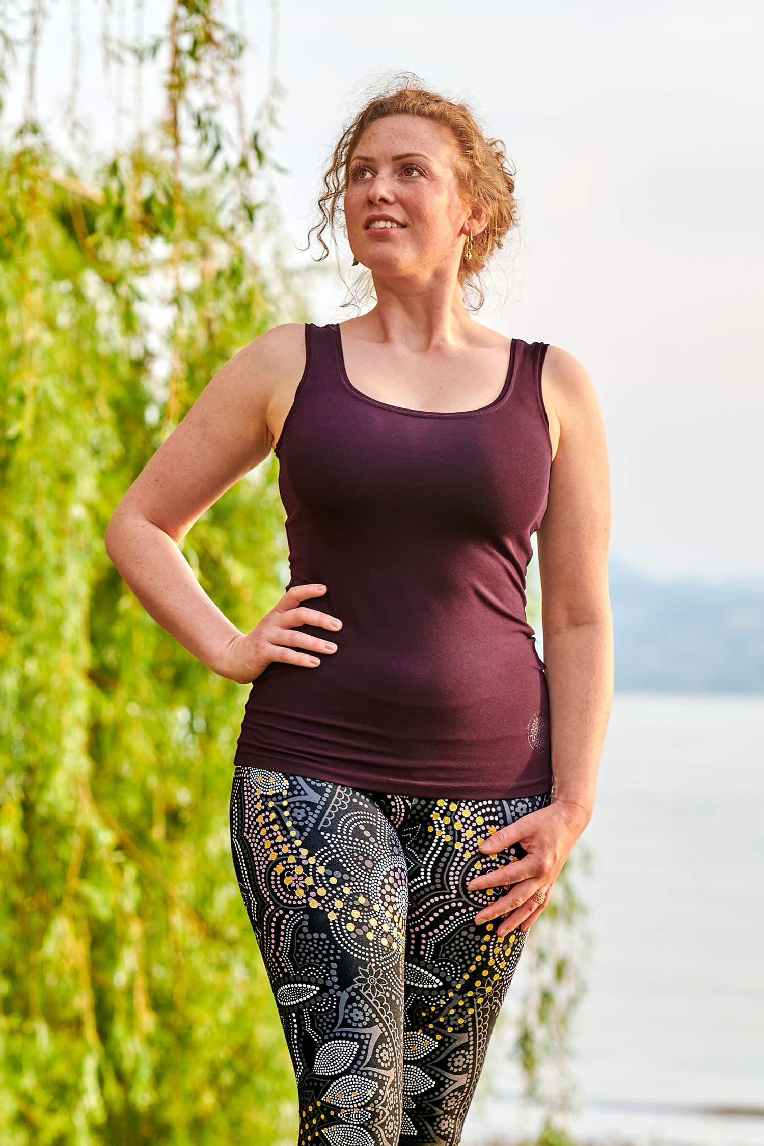 Yoga-Top aubergine Gr. M Frau trägt ein lila Yoga Top aus bio Baumwolle (kbA) und Elasthan mit grau gemusterter Leggings