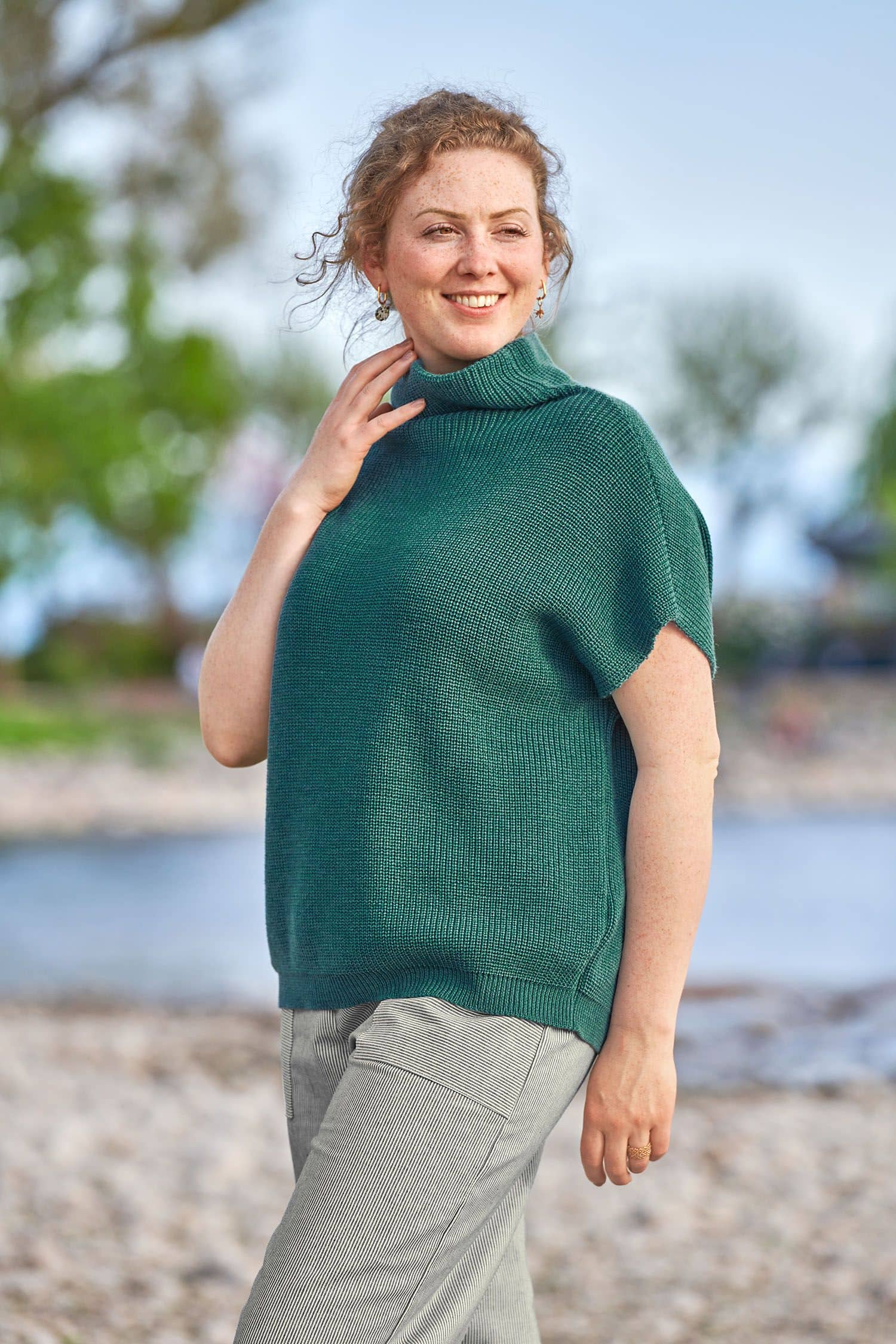 Frau mit Stoffhose trägt petrolfarbenen Strickpullunder aus bio Wolle (kbT)  vom Finkhof