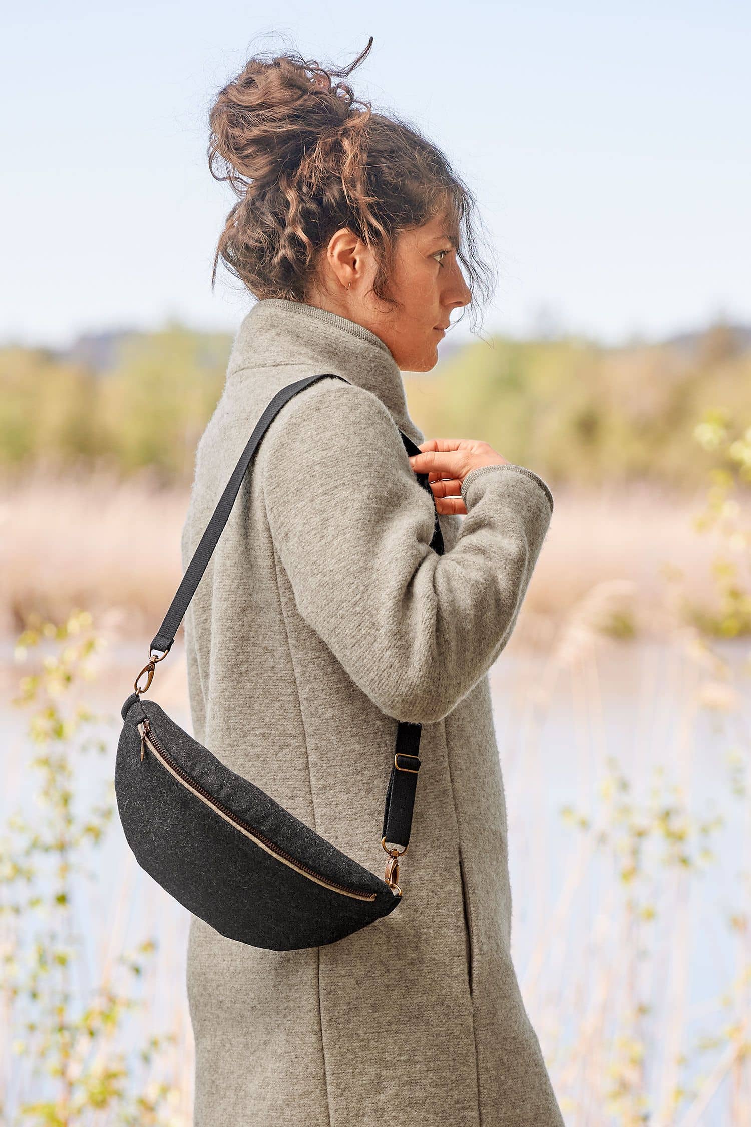 Frau mit grauem Mantel hat sich die anthrazitgraue Schultertasche aus Loden (Webstoff aus Schurwolle) vom Finkhof umgehängt