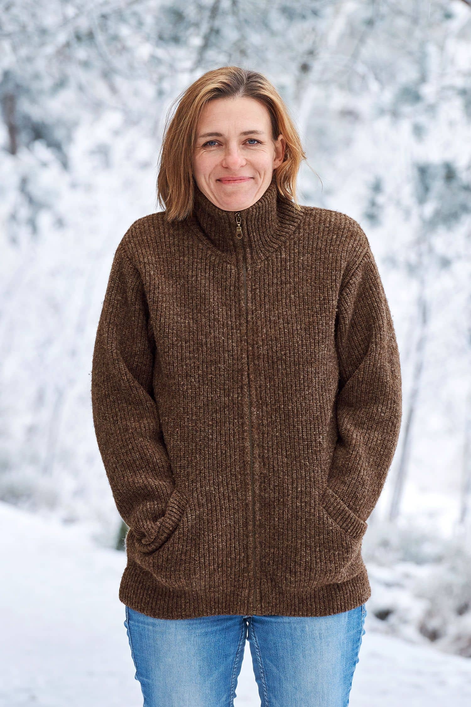 Frau in Schneelandschaft trägt eine braune Finkhof Jacke aus bio Wolle (kbT)