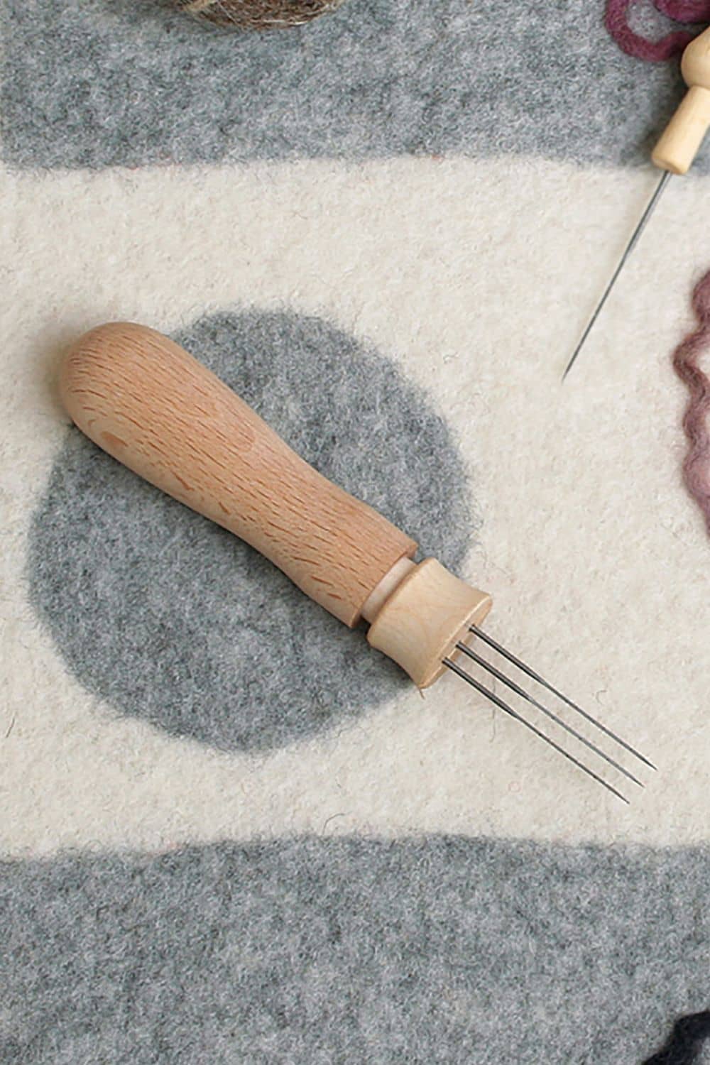 Filznadelhalter "Profi" Filznadelhalter Profi für bis zu drei Nadeln mit Holzgriff auf grau gemustertem Untergrund