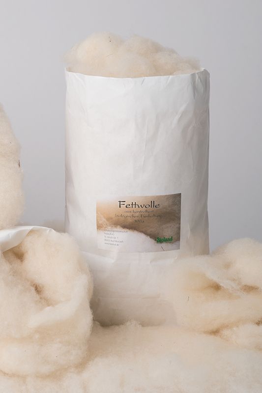 Fettwolle 100 g (kbT) weiße Fettwolle aus bio Wolle (kbT) vom Finkhof in überquellender 100g Papierverpackung , davor liegen weitere Wollstücke