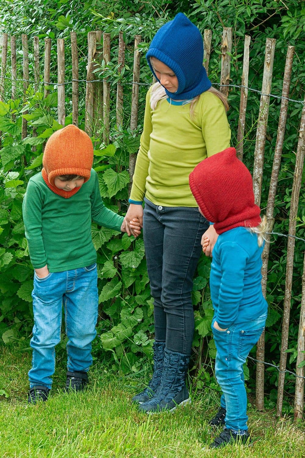 Kinder stehen im Garten und tragen Shirts und Schlupfmützen aus bio Wolle (kbT) und bio Baumwolle (kbA) vom Finkhof