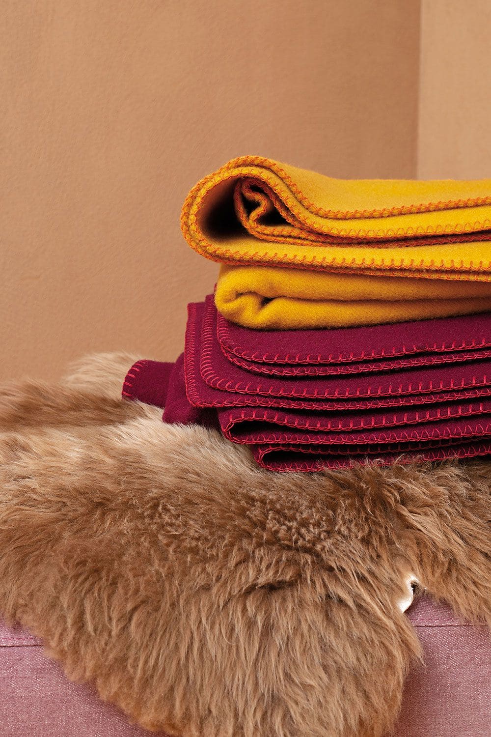 Regionale Wolldecke farbig Zwei Finkhof Wolldecken übereinander auf einem Schaffell gelegt