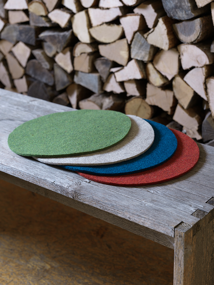Finkhof-Sitzauflagen aus Nadelfilz rund runde Finkhof Sitzauflagen in verschiedenen Farben aus bio Wolle (kbT) auf einer Holzbank