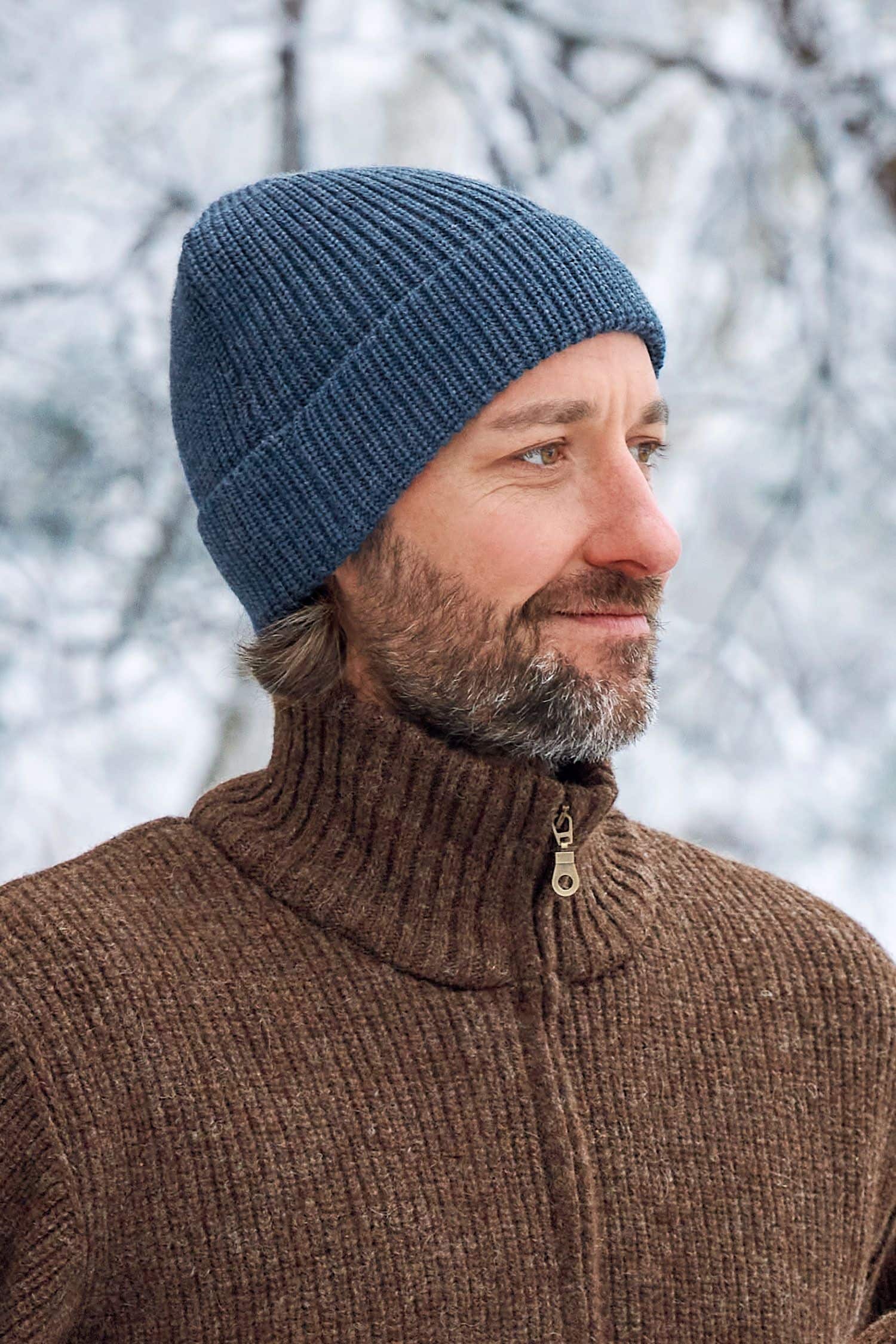 Mann trägt jeansblaue Finkhof Mütze aus bio Wolle (kbT) und braunen Finkhof Troyer