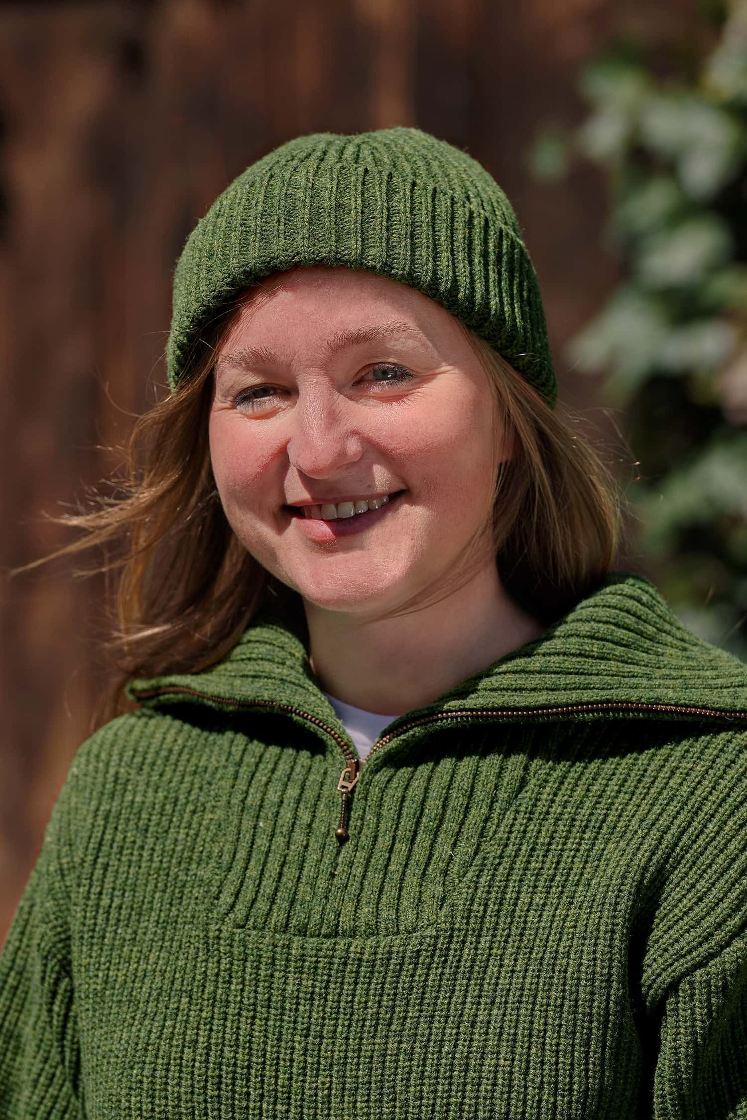 Frau trägt einen grünen Troyer und eine grüne Fischermütze aus Bio-Wolle vom Finkhof
