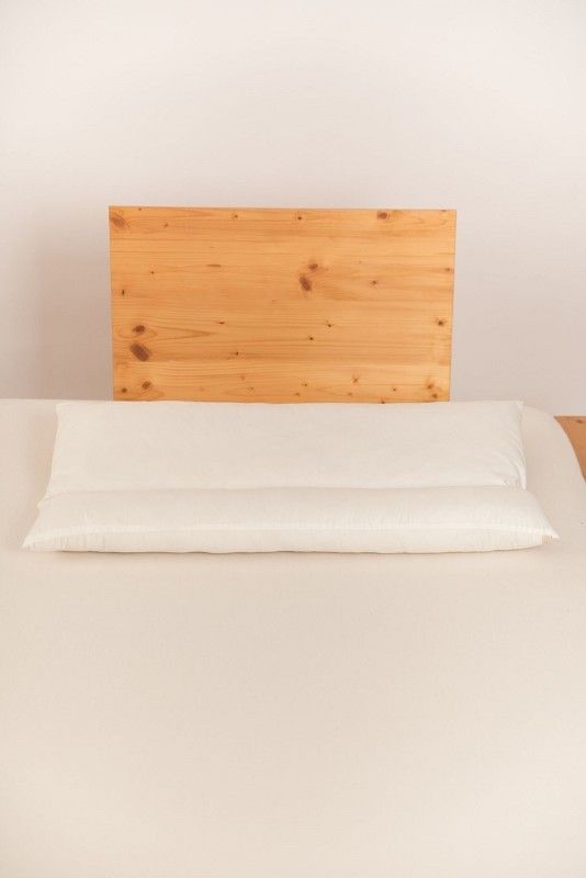 weißes Rollenkissen in 40x80cm aus bio Wolle (kbT) und bio Baumwolle (kbA) vom Finkhof auf hellbraunem Bett