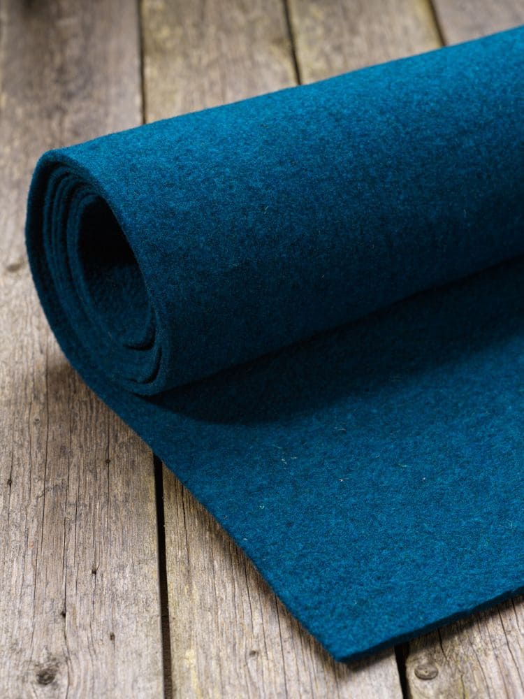 Finkhof-Nadelfilz seeblau blaue Rolle Finkhof Nadelfilz aus bio Wolle (kbT) auf braunem Holzboden