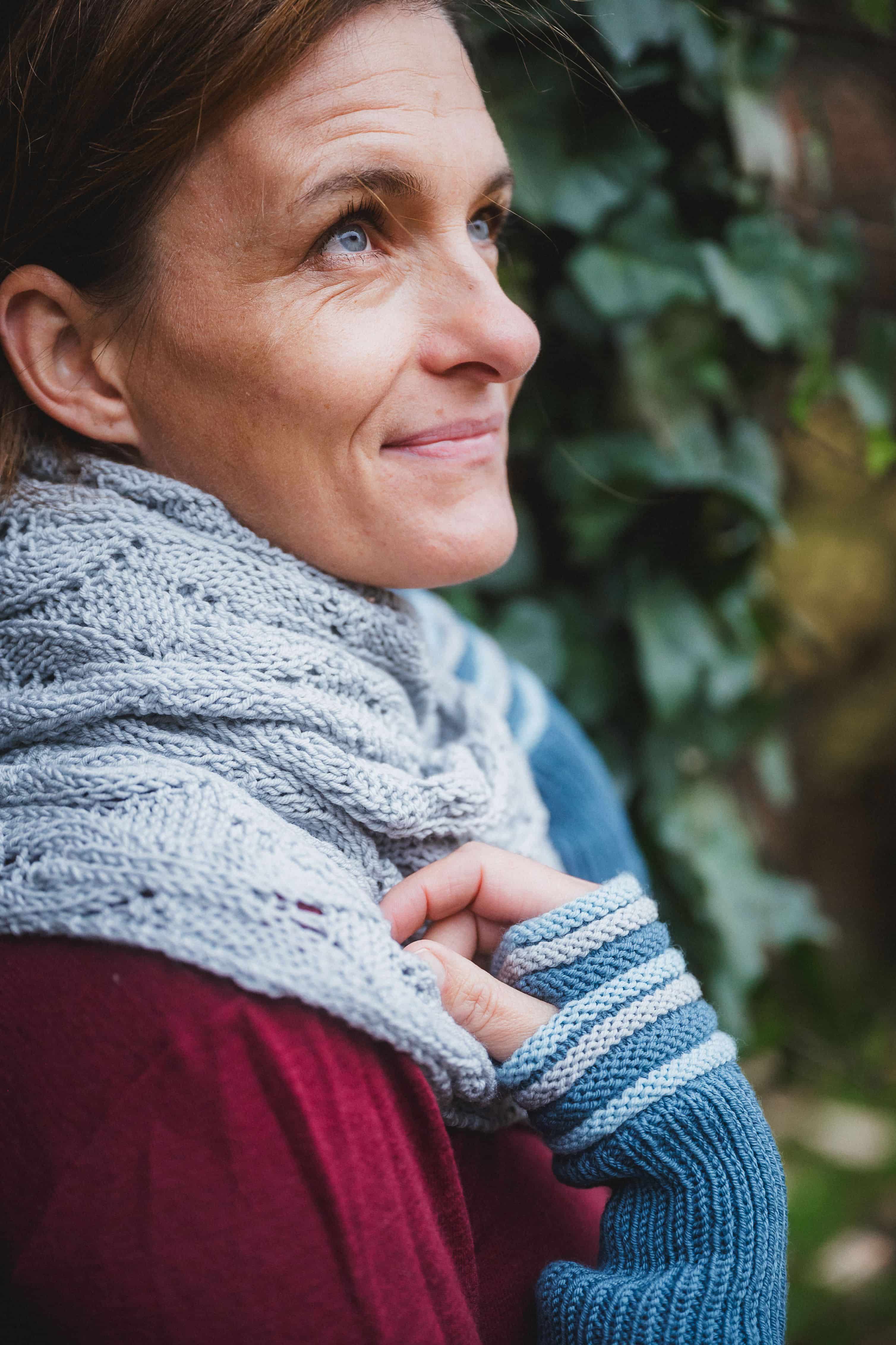 Frau trägt rotes Shirt, blaue Stulpen und blaues Tuch mit Ajourmuster