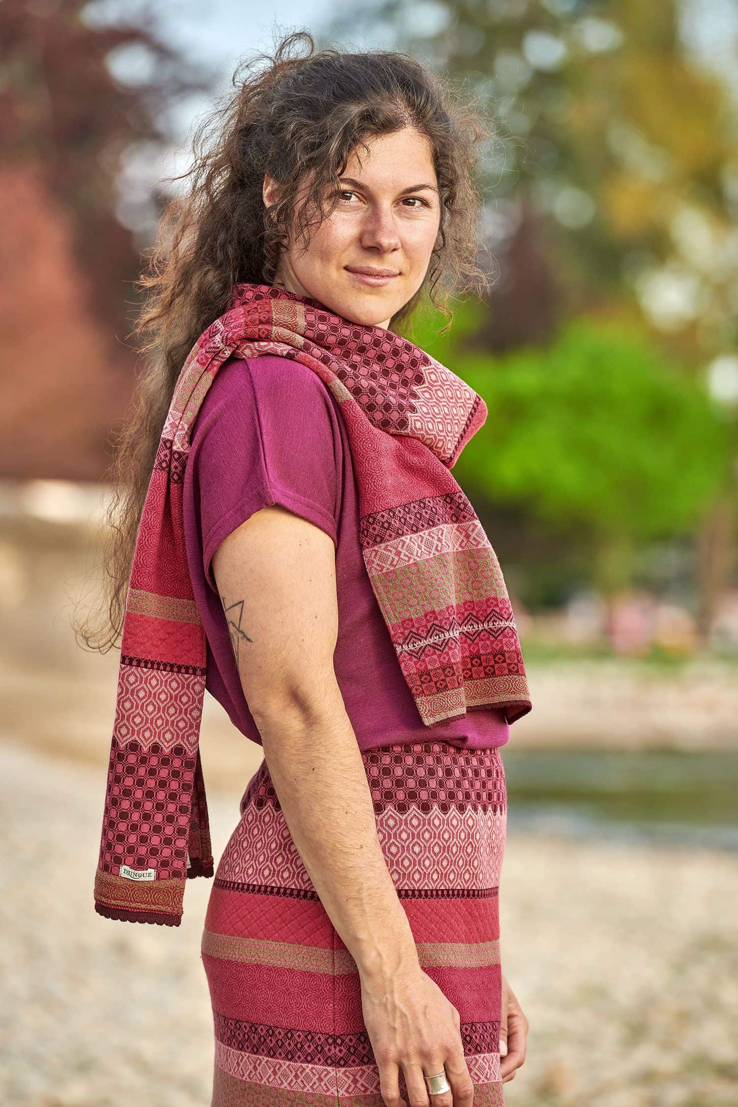 Frau trägt gemusterten Strickschal aus bio Baumwolle (kbA) in beere und pink, einen Rock und ein Shirt
