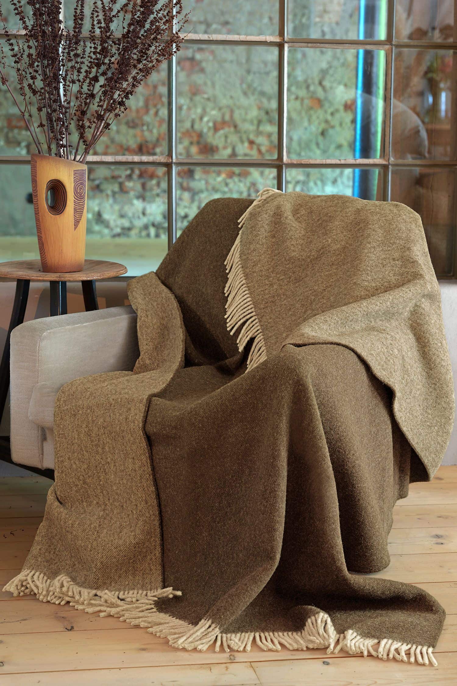 Wollplaid braun/hellbraun 150 x 210 cm braunes Wollplaid mit Fraunsen aus bio Wolle (kbT) auf hellgrauem Sessel