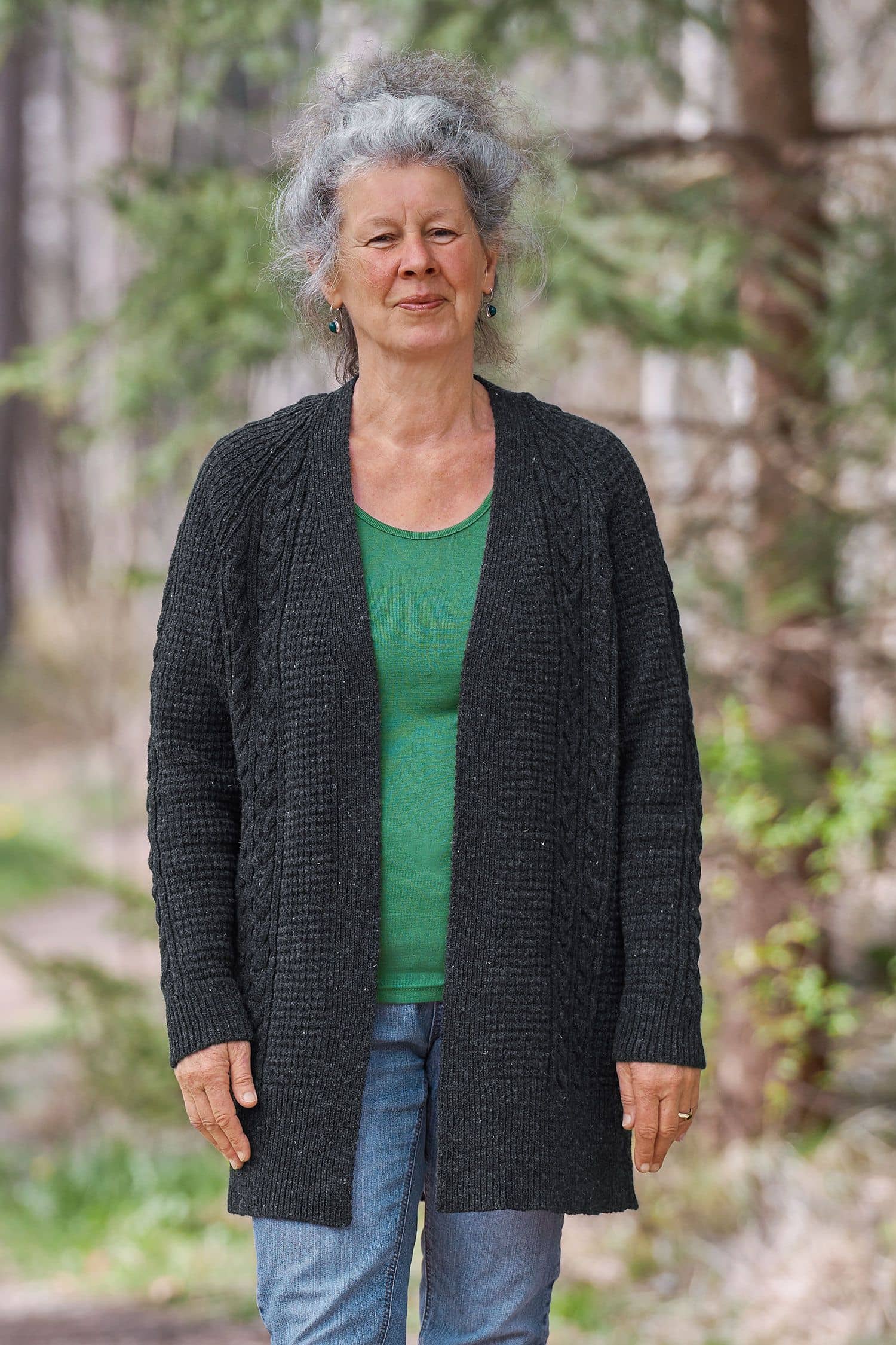 Frau trägt anthrazitfarbenen Cardigan vom Finkhof mit Zopfmuster aus bio Wolle (kbT) und grünes Shirt