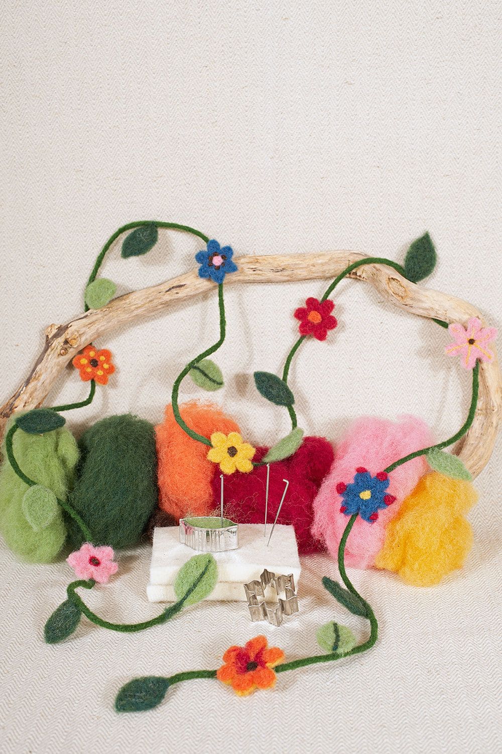 Stimmungsbild von fertiger Blumenranke aus bio Wolle (kbT) vom Finkhof mit Ast, Filzknäulen und Trockenfilzutensilien