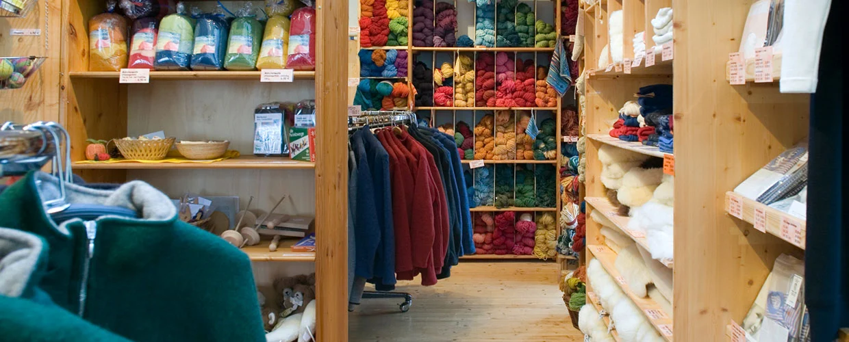 Finkhof Motiv zum Einstieg für den Hofladen mit vollen Wollregalen und Kleiderstangen