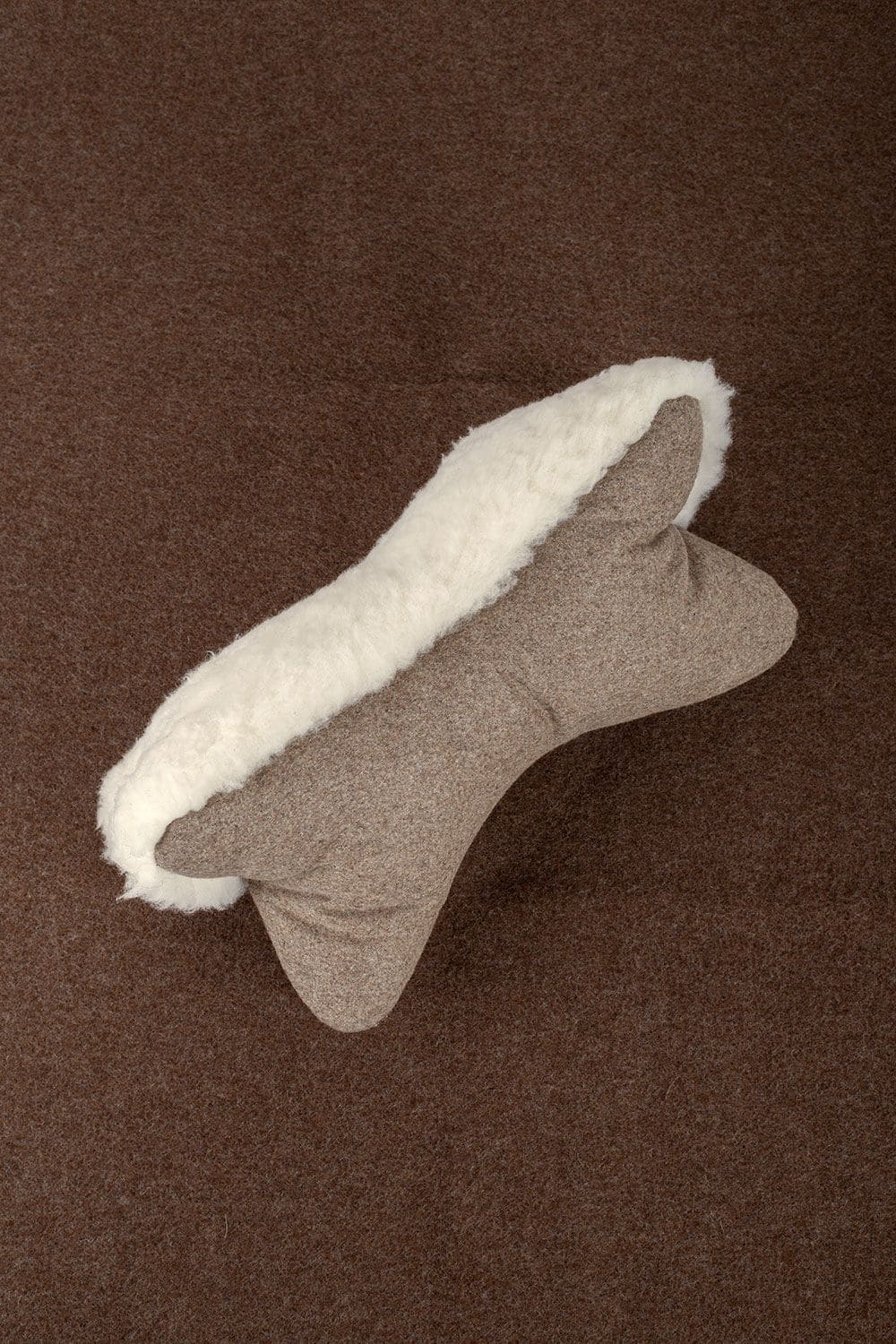 Finkhof Leseknochen aus Schaffell, Loden und Rohwolle (kbT) liegt auf braunem Untergrund